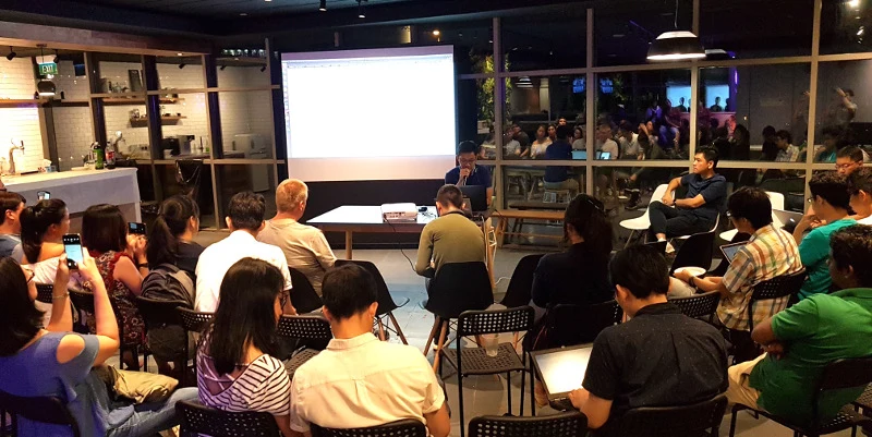 Nasrudin Salim conducting a data science workshop in front of a seated audience and a projection screen